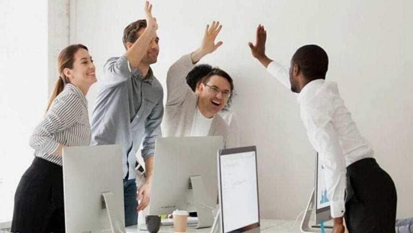 Un groupe de personnes levant les mains en l’air dans un bureau.