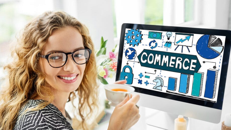 Une femme avec des lunettes, souriante et tenant une tasse, est assise à un bureau avec un ordinateur affichant diverses icônes liées au commerce.