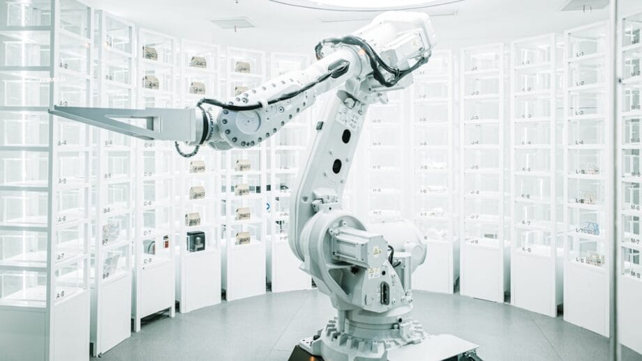 Un bras robotique élégant dans un laboratoire moderne et bien éclairé rempli de rangées organisées de conteneurs.