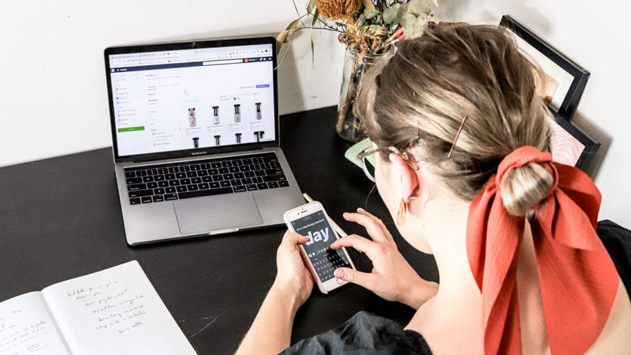 Une femme assise à un bureau avec un ordinateur portable et un téléphone portable.