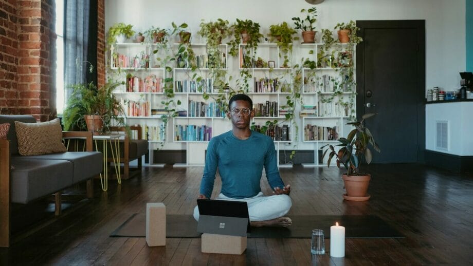 Une personne est assise sur un tapis de yoga dans un salon avec un ordinateur portable Windows.