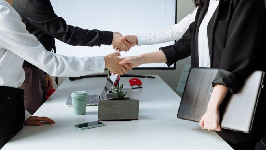 Quatre personnes serrant la main sur une table dans un environnement de bureau, suggérant un accord ou une salutation professionnelle.