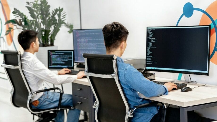 Deux hommes travaillant sur des ordinateurs dans un bureau.