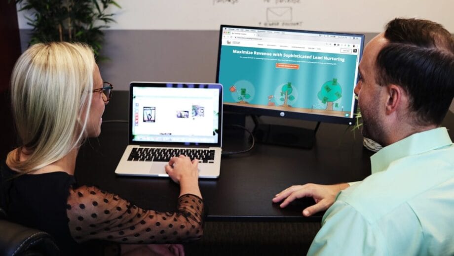 Deux personnes sont assis à un bureau, visualisant un ordinateur portable et un moniteur affichant un site Web de développement.