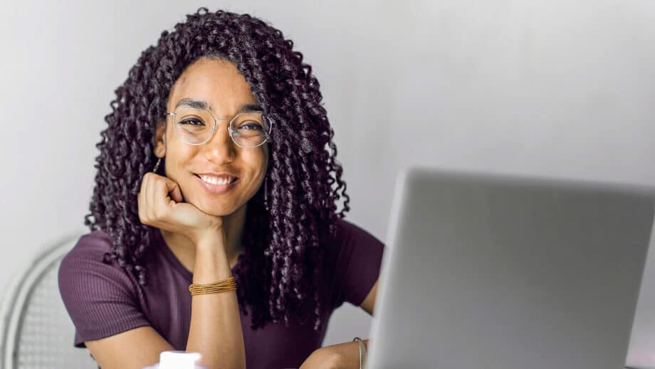 Une femme aux cheveux bouclés assis à un bureau avec un ordinateur portable.