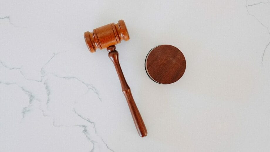 Un marteau de juge en bois et un bloc sonore sur une surface en marbre blanc essayant de justifier les preuves générées par l'IA.
