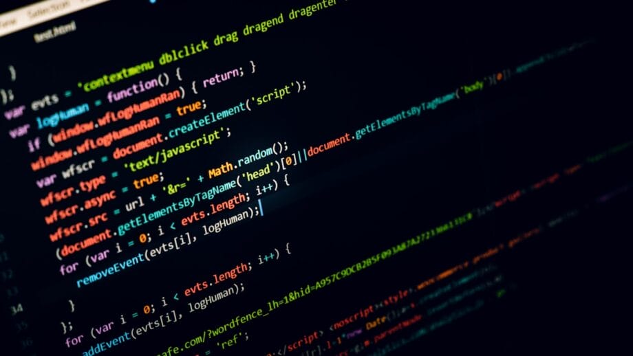 Un écran d’ordinateur affiche des lignes colorées de code JavaScript sur un fond sombre.