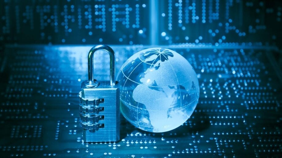 Un cadenas à combinaison et un globe en verre reposent sur un circuit imprimé, symbolisant la cybersécurité et la protection des données.