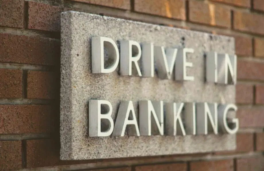 Panneau en pierre sur un mur de briques avec des lettres en relief indiquant DRIVE IN BANKING.