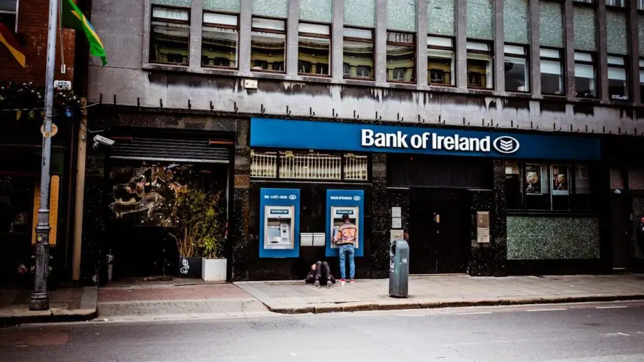 Personne utilisant un guichet automatique à l'extérieur d'une succursale de la Bank of Ireland dans une rue de la ville pendant la journée.