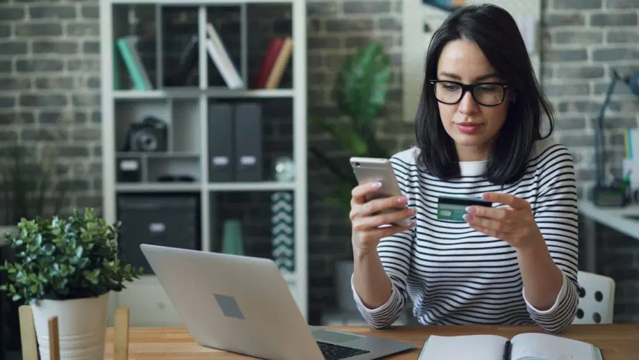 une femme assise à une table regardant son téléphone portable