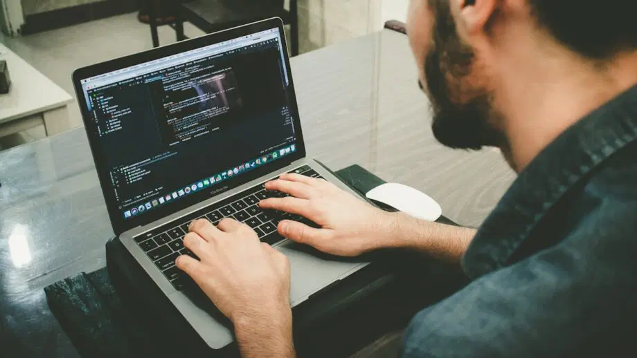 Un homme travaille sur un ordinateur portable avec du code dans l’un des langages de programmation les plus populaires à l’écran.